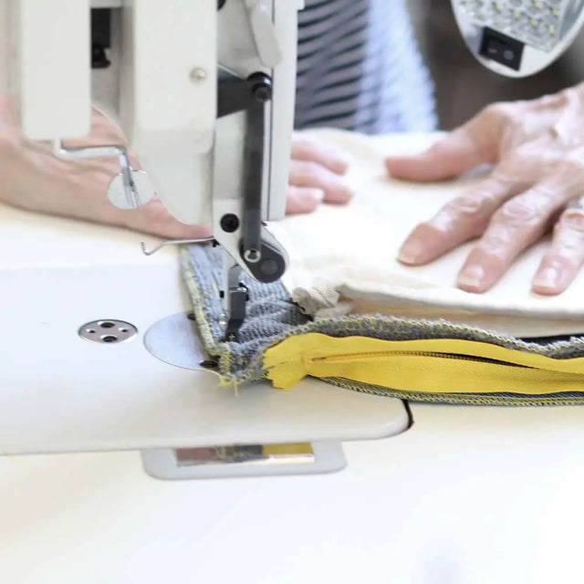 Eine Näherin in einer Werkstatt für Menschen mit Behinderung sitzt an einer Nähmaschine und fertigt ein nachhaltiges Hundebett aus recycelten PET-Flaschen von BUDDY. Hundezubehör. Eine Näherin in einer Werkstatt für Menschen mit Behinderung sitzt an einer Nähmaschine und fertigt ein nachhaltiges Hundebett aus recycelten PET-Flaschen von BUDDY. Hundezubehör.