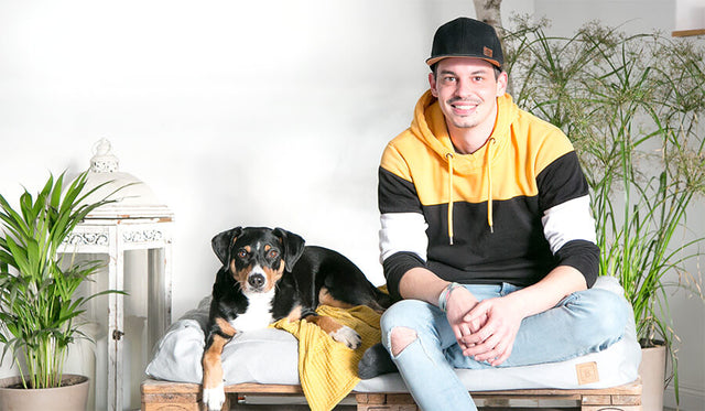 Manuel Mohlberg der Gründer von BUDDY. Hundezubehör sitzt mit seiner Appenzeller Sennenhündin auf einem nachhaltigen Hundebett