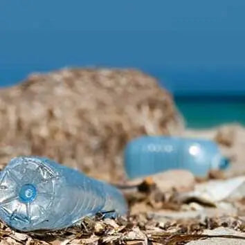 Blaue Plastikflaschen liegen am Strand und verschmutzen die Umwelt.